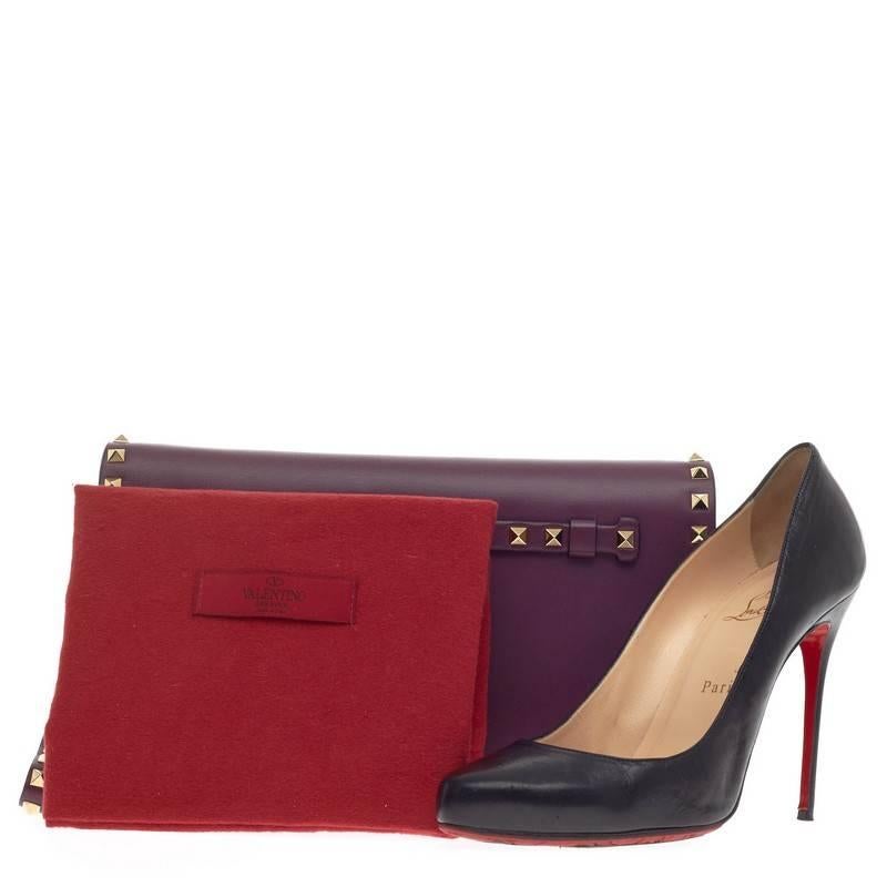 This authentic Valentino Rockstud Flap Clutch Leather is a chic yet functional accessory perfect for on-the-go moments. Crafted in beautiful purple calfskin leather, this trendy clutch features polished gold Valentino signature rockstuds detailing,