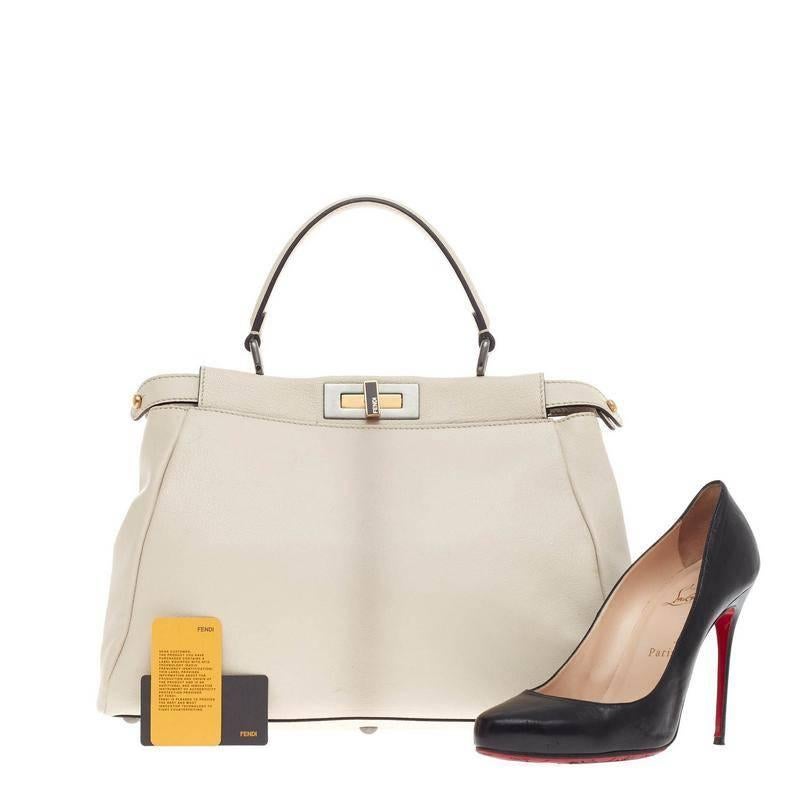 This authentic Fendi Peekaboo Leather Regular is one of Fendi's best known design exuding a luxurious yet minimalist appearance. This eggshell white leather satchel is accented with a subtle ombre shaded gray spine down the center, a top frame