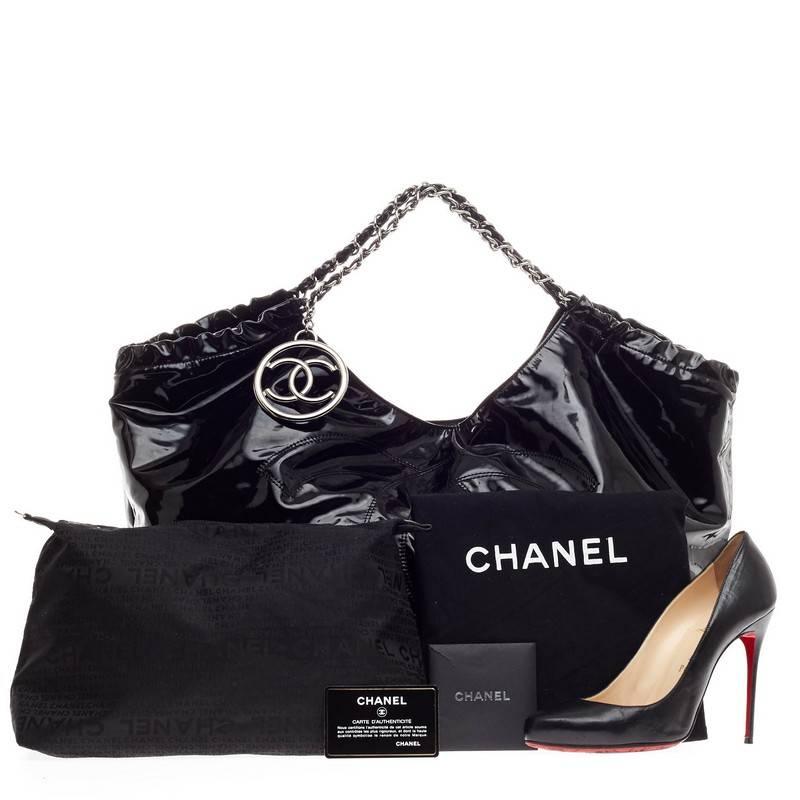 This authentic Chanel Coco Cabas Patent XL is finely crafted in black patent leather perfect for your daily outfit. This oversized, roomy hobo features a large subtly, stitched Chanel CC frontal logo, ruching detail and woven-in leather chain