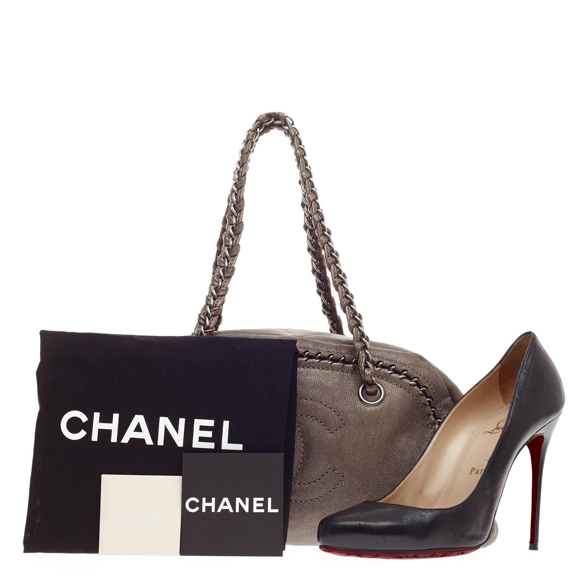 This authentic Chanel Luxe Ligne Bowler Leather Medium is perfect for an on-the-go fashionista. Constructed from metallic taupe-gray leather, this dome-shaped shoulder bag features braided woven leather silver chain straps, stitched chain edges with