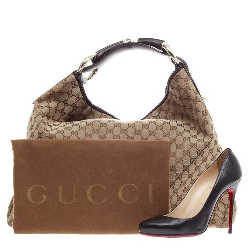 Questa autentica Horsebit Hobo GG Canvas Large di Gucci è un modello iconico che aggiunge un tocco glamour al tuo look casual. Fabrice in tela Monogram di Gucci, questa borsa è caratterizzata da manico e finiture in pelle marrone scuro, finiture