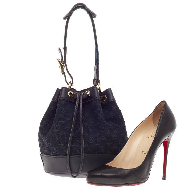 This authentic Louis Vuitton Noelie Mini Lin is an understated bucket bag made for daily excursions. Crafted in signature navy blue monogram mini lin canvas, this drawstring bag features navy leather trims, navy adjustable shoulder strap with