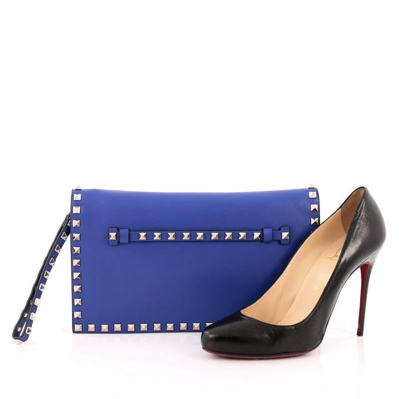 This authentic Valentino Rockstud Flap Clutch Leather is a chic yet functional accessory perfect for on-the-go moments. Crafted from blue leather, this trendy clutch features a leather hand sling, back studded hand strap, polished gold Valentino