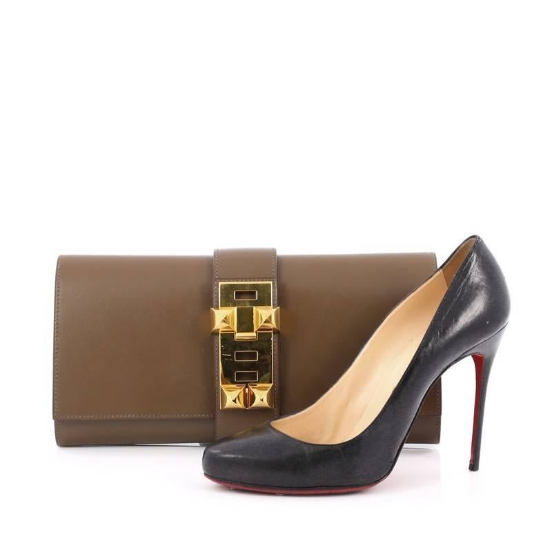This authentic Hermes Medor Clutch Box Calf 29 is a hard-to-get, modern piece inspired by the brand's iconic 'collier de chien' hardware. Crafted from vert olive smooth box calf leather, this elegant clutch features a simple silhouette, with