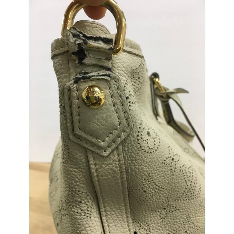 This authentic Louis Vuitton Stellar Handbag Mahina Leather PM displays understated simplicity and elegance with versatile functionality made for the modern woman. Crafted from off-white perforated mahina leather, this soft-structured tote features