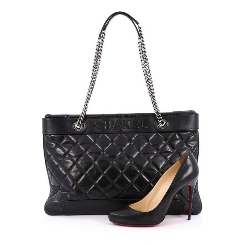 This authentic Chanel Aged Chain Logo Shopping Tote Quilted Aged Calfskin Large mixes a sophisticated and elegant style with modern accents. Crafted from black diamond quilted aged calfskin leather, this chic tote features dual woven-in leather