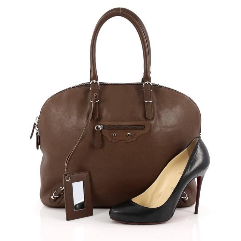 This authentic Balenciaga Carousel Bowling Bag Classic Studs Leather Large is a chic bag with bold style. Constructed in brown leather, this bowling bag features a rounder silhouette, dual-rolled leather handles, zipped front pocket, the brand's