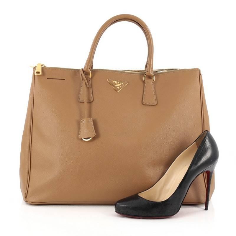 This authentic Prada Double Zip Lux Tote Saffiano Leather Large is a perfect bag to complete any outfit. Crafted from caramel brown saffiano leather, this boxy tote features side snap buttons, raised Prada logo, dual-rolled leather handles and
