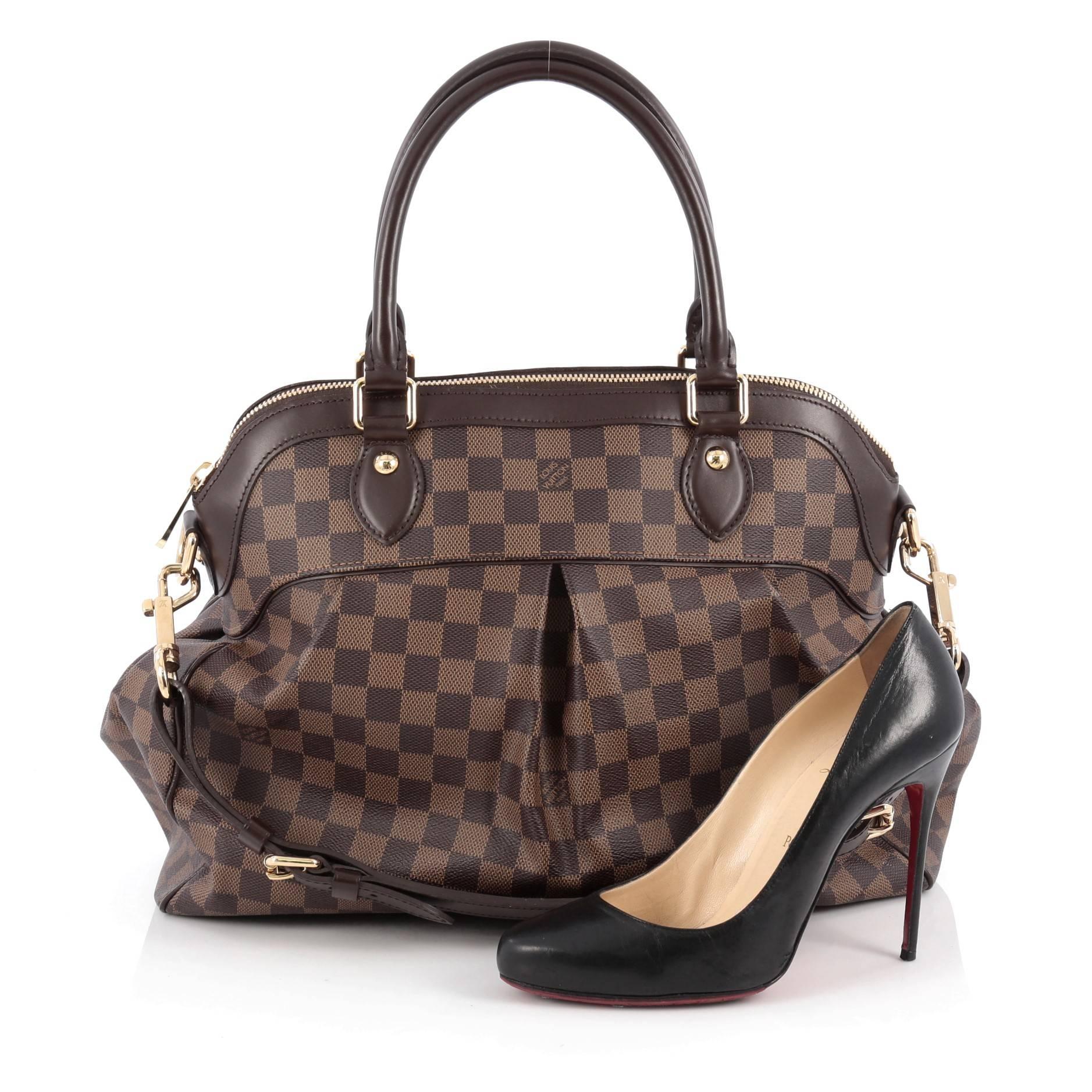 This authentic Louis Vuitton Trevi Handbag Damier GM inspired by the Trevi Fountain is a chic and versatile handle bag. Crafted from classic damier ebene coated canvas, this tote features dual-rolled handles, brown leather trims, subtle pleats in