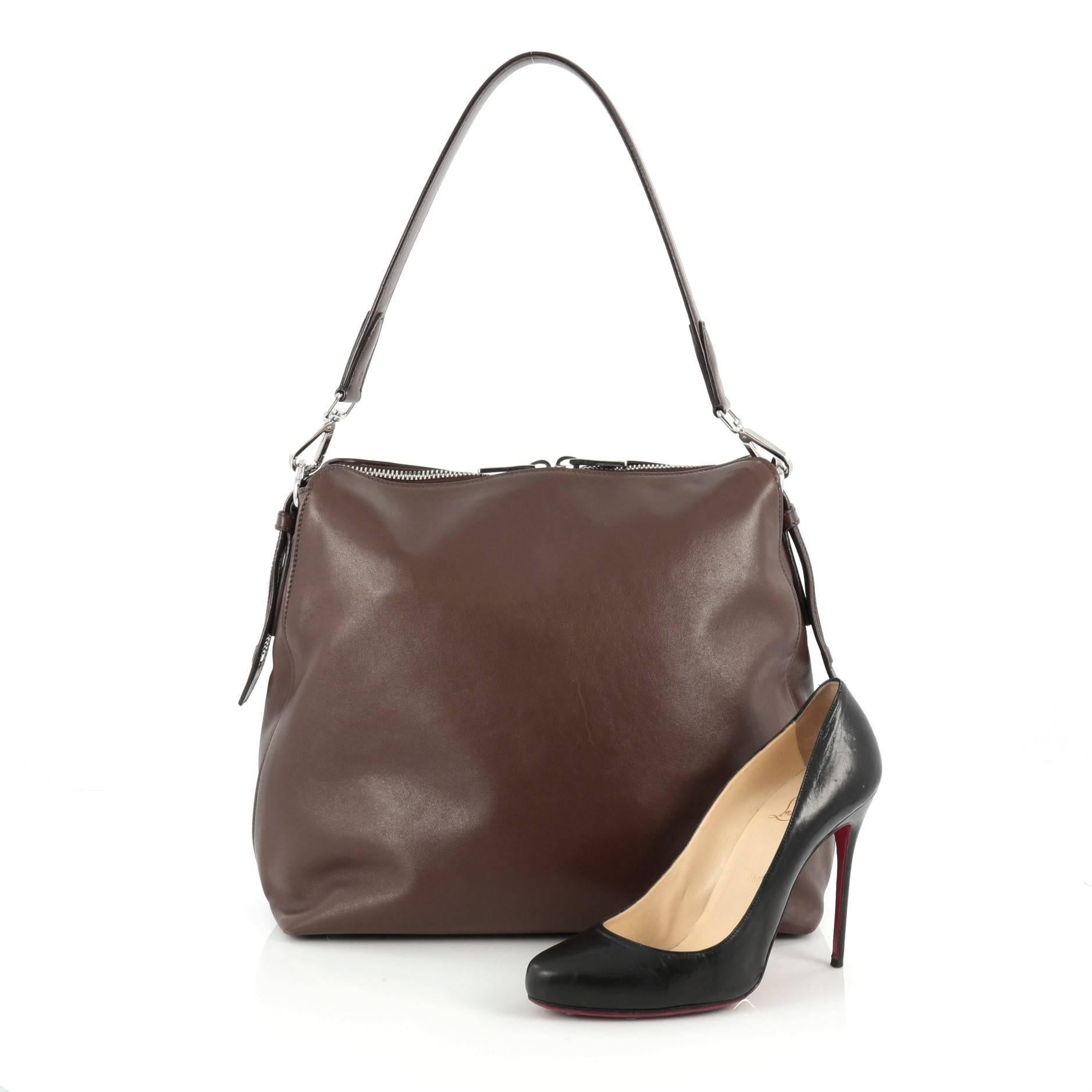 This authentic Prada Zip Top Hobo Soft Calfskin Large is a classic and practical bag made for everyday excursions. Constructed in brown calfskin leather, this simple hobo features a flat leather shoulder strap, Prada logo, protective base studs and
