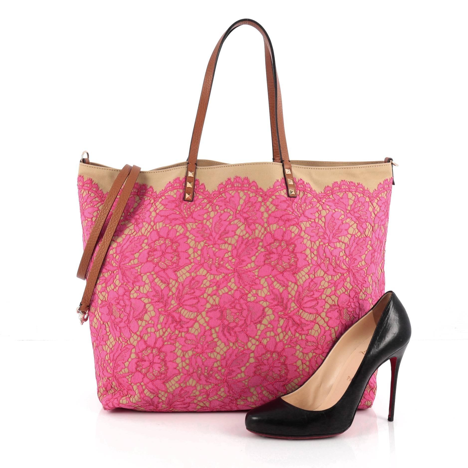 This authentic Valentino Glam Rockstud Reversible Tote Lace and Canvas displays an unexpected touch of romance to a spacious tote. Crafted from reversible beige canvas with pink lace overlay, this feminine bag features dual slim leather handles with