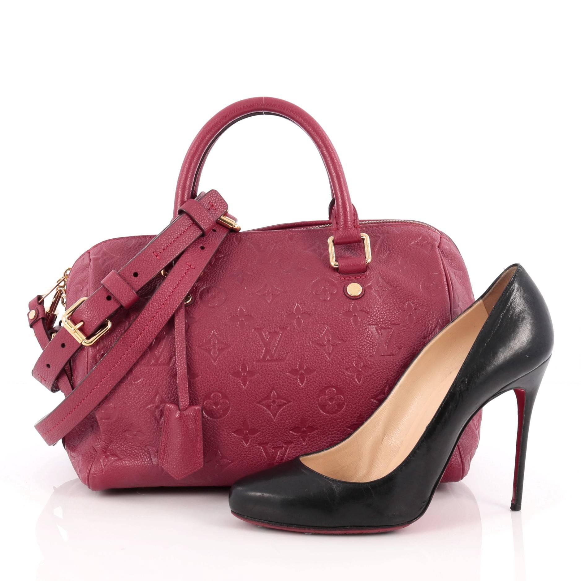 This authentic Louis Vuitton Speedy Bandouliere Bag Monogram Empreinte Leather 25 is a modern must-have. Constructed from Louis Vuitton's luxurious jaipur raspberry red monogram embossed empreinte leather, this iconic and re-imagined Speedy features