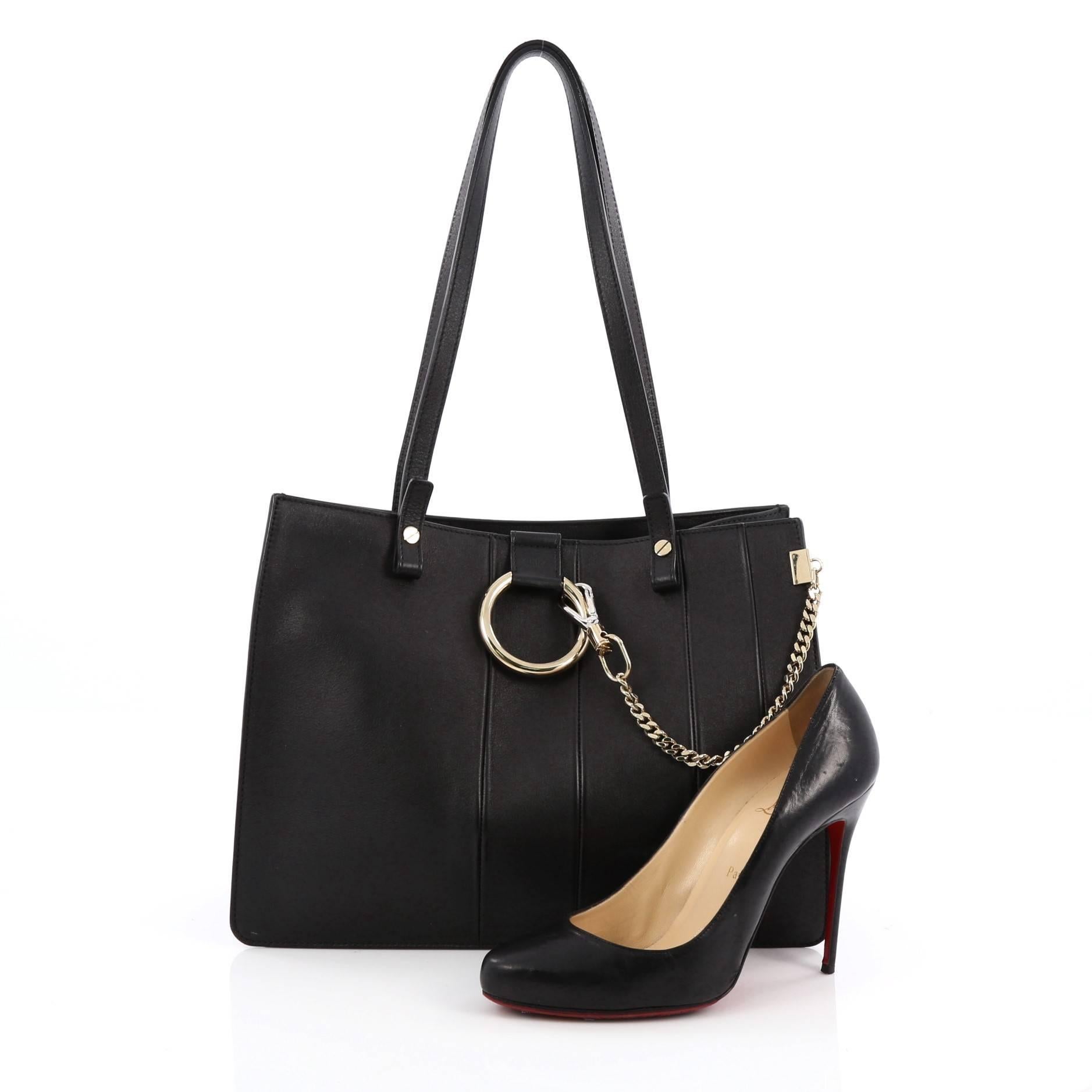 This authentic Chloe Faye Tote Stitched Leather Small personifies Chloe's unique luxe bohemian aesthetic with a minimalist spin. Crafted from black leather, this sleek, stylish tote features dual-flat leather handles, ring with chain, stamped logo