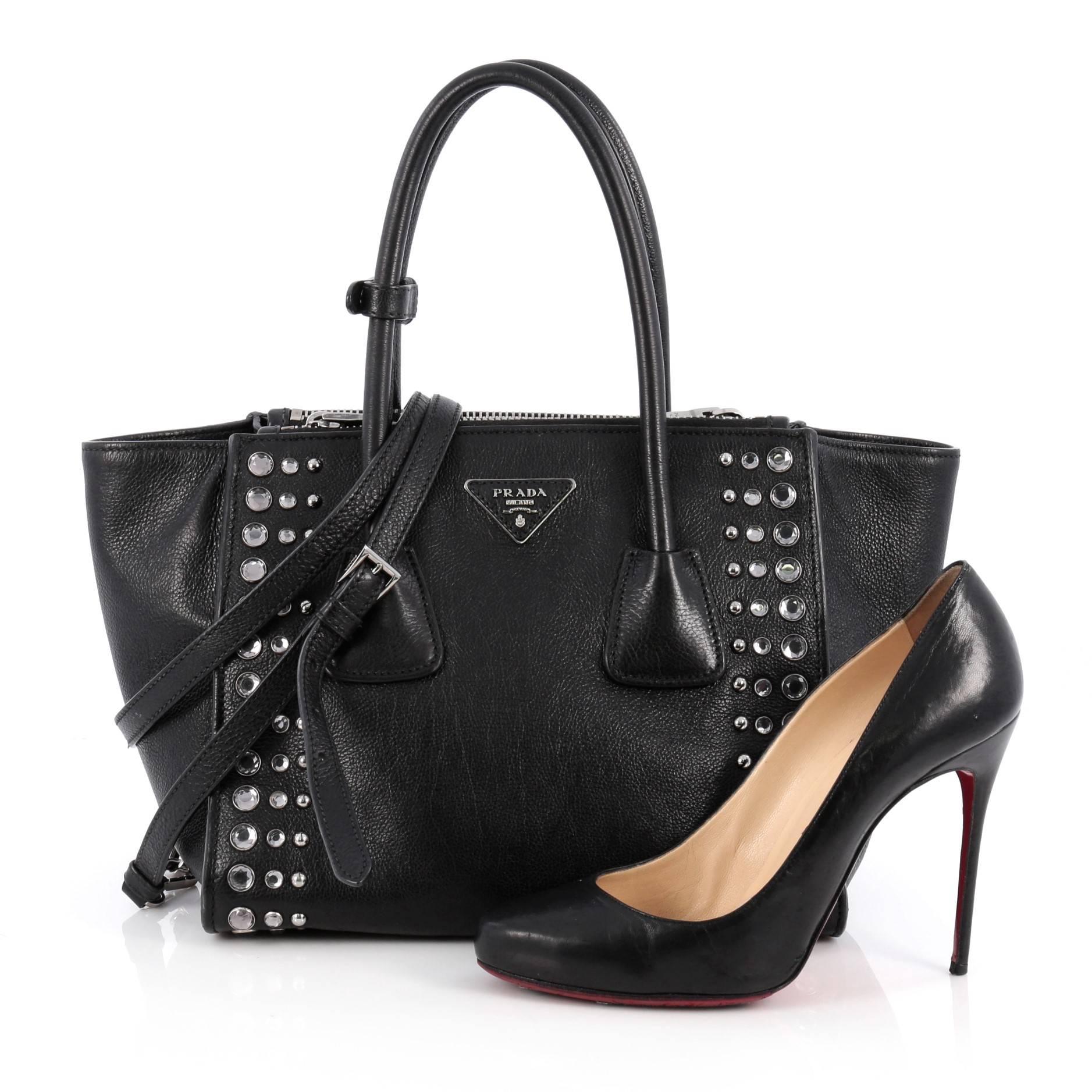This authentic Prada Twin Pocket Tote Studded Glace Calf Small showcases a sophisticated silhouette balancing modern luxury and style. Crafted from black glace calf leather, this boxy tote features tall dual-rolled top handles, extended sides,