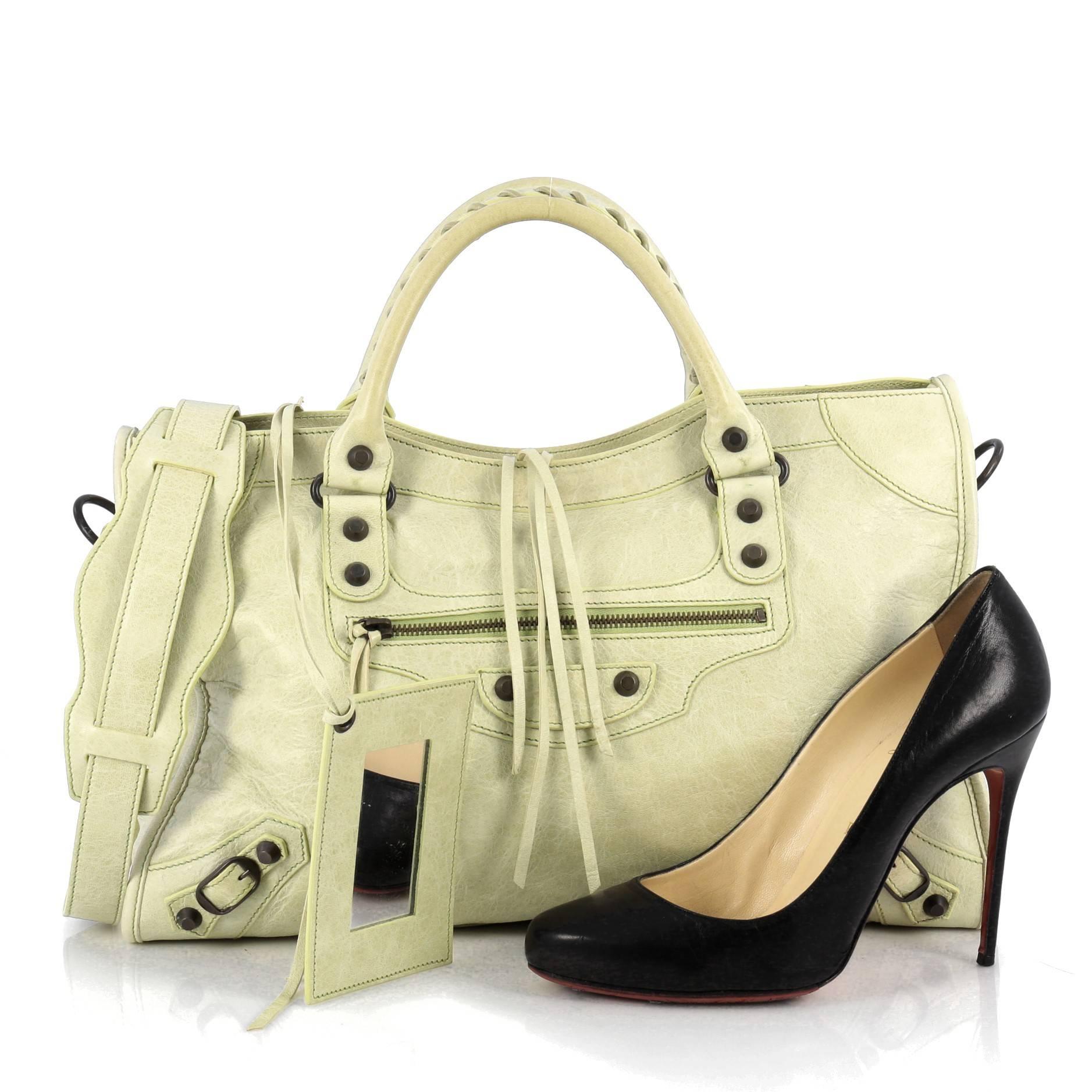 This authentic Balenciaga City Classic Studs Handbag Leather Medium is for the on-the-go fashionista. Constructed in lime green leather, this popular bag features dual braided woven handle straps, front zip pocket, iconic Balenciaga classic studs