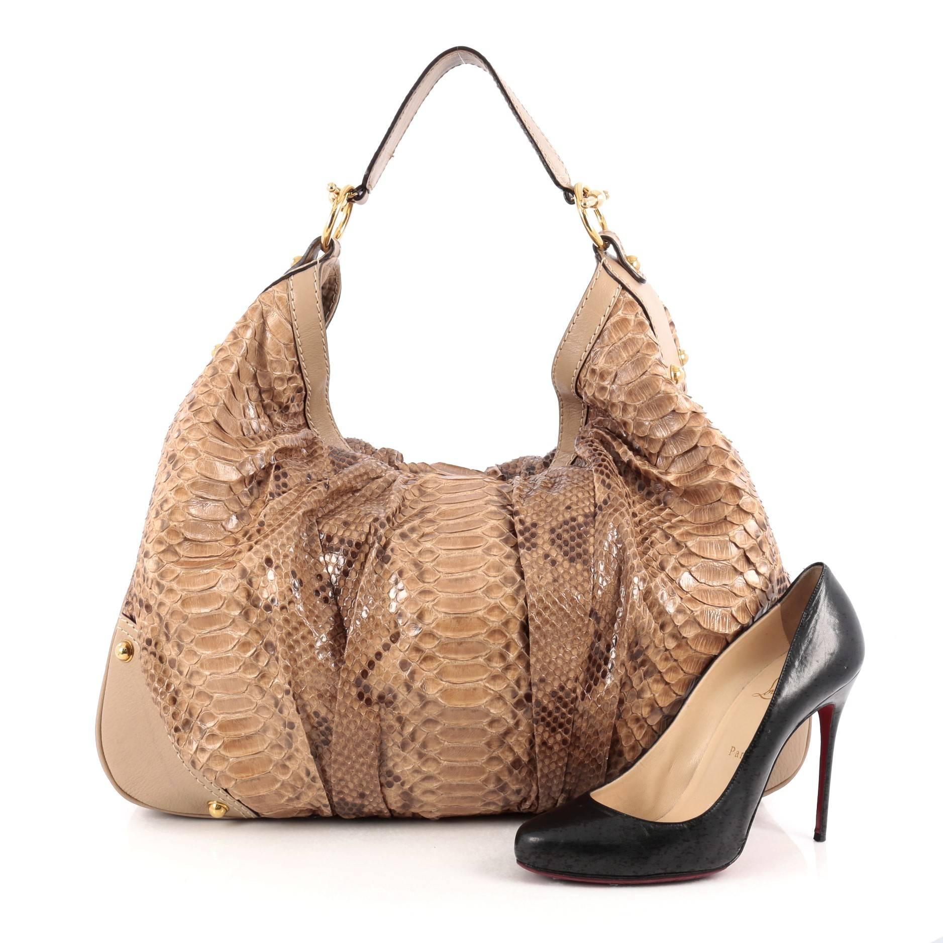 This authentic Gucci Jockey Hobo Python Large is unique and sophisticated in design perfect for everyday casual use. Crafted in brown genuine python skin, this hobo features a wide leather handle, brown leather trims, Gucci side ring details, gold