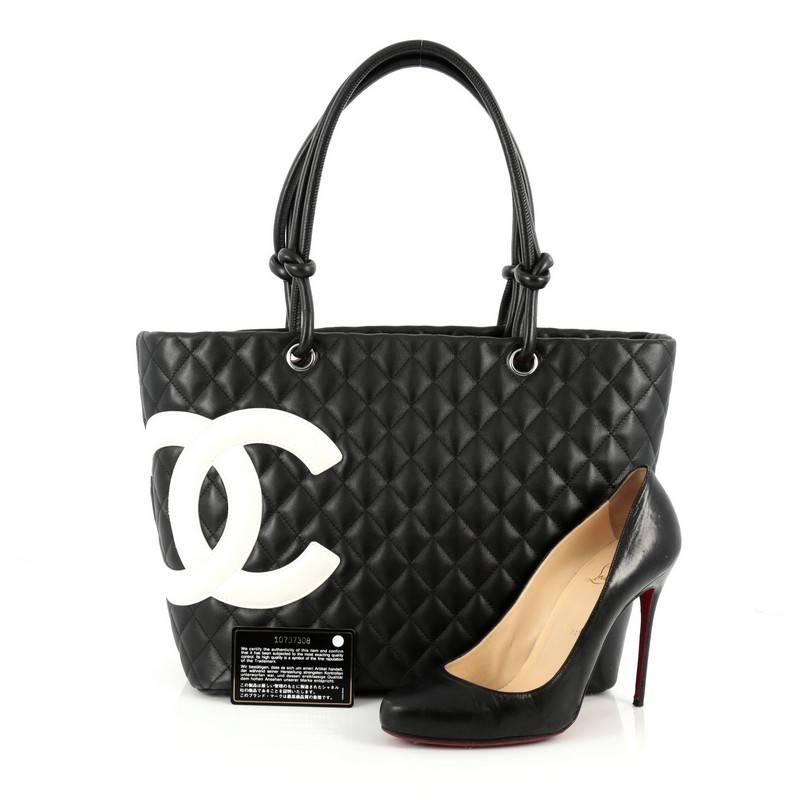 This authentic Chanel Cambon Tote Quilted Leather Large is a finely crafted bag from the brand's Cambon Collection. Crafted from black diamond quilted leather, this tote displays a large white leather interlocking CC side logo, dual-rolled black