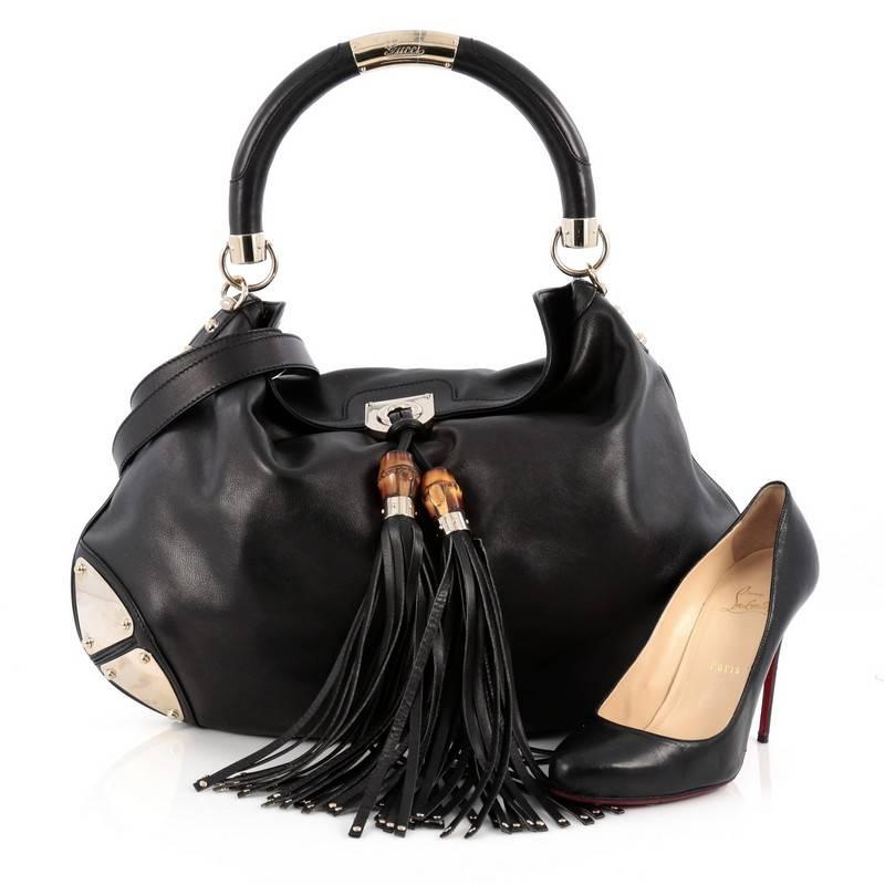 This authentic Gucci Indy Hobo Leather Large showcases the brand's classic design with luxurious detailing adding an industrial chic twist. Crafted from black leather, this eye-catching hobo features bamboo and fringe tassels, GG print leather trims