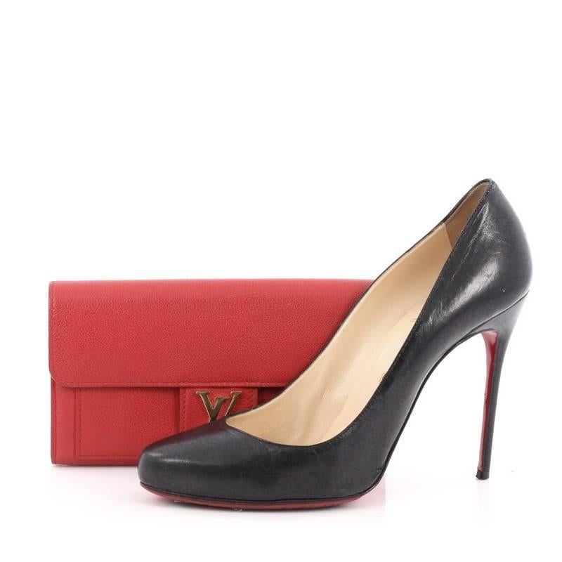 This authentic Louis Vuitton Lockme Wallet Calfskin is your perfect small accessory. Crafted in red calfskin leather, this chic wallet features a frontal flap with LV logo and gold-tone hardware accents. Its snap button closure opens to a middle zip