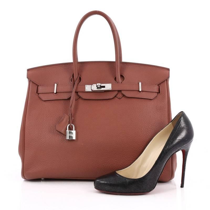 This authentic Hermes Birkin Handbag Sienne Togo with Palladium Hardware 35 stands as one of the most-coveted bags. Constructed from scratch-resistant, iconic sienne red togo leather, this stand-out tote features dual-rolled top handles, frontal