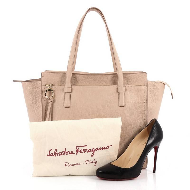 This authentic Salvatore Ferragamo Amy Tote Pebbled Leather Medium is a spacious everyday bag that is a fantastic addition to any collection. Crafted from nude pebbled leather, this timeless tote features dual flat shoulder strap, exterior front zip