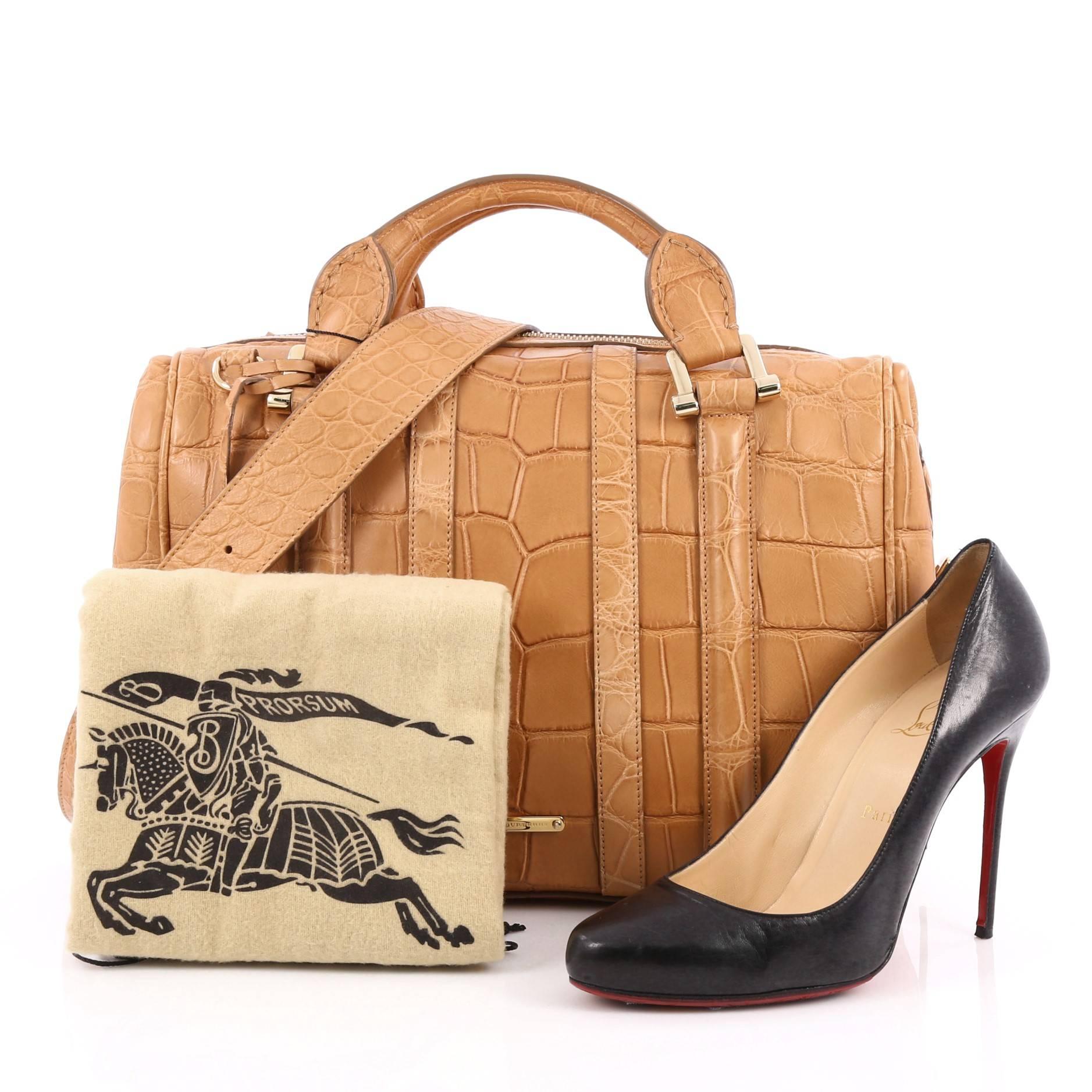 This authentic Burberry Nevinson Bowling Bag Alligator Medium is a sleek bowling bag that can be a fantastic addition to your wardrobe. Crafted from genuine brown alligator skin, this bag features dual-rolled handles, removable adjustable flat