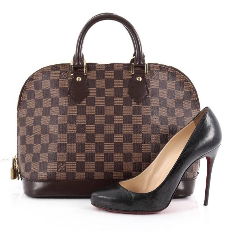 This authentic Louis Vuitton Vintage Alma Handbag Damier PM is an elegant spin on a classic style that is perfect for all seasons. Crafted from Louis Vuitton's damier ebene coated canvas, this dome-shaped satchel features dual-rolled handles, dark