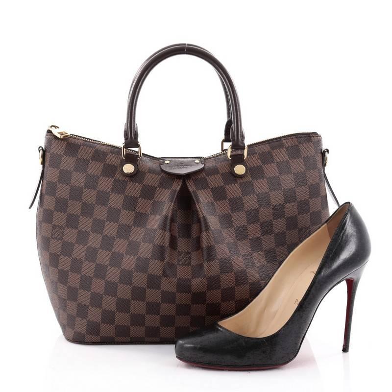 This authentic Louis Vuitton Siena Handbag Damier MM is an elegant go-everywhere bag for busy lifestyles. Crafted from damier ebene coated canvas, this stylish bag features dual-rolled leather top handles with gold links, removable, adjustable