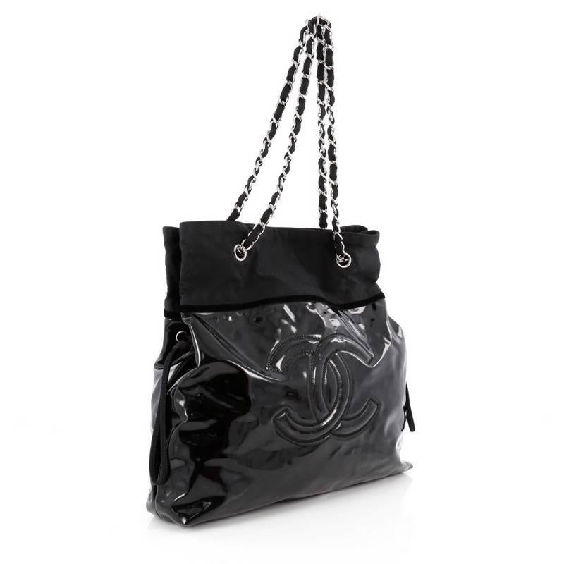 This authentic Chanel Stretch Spirit Drawstring Tote Patent Vinyl is perfect for on-the-go moments. Crafted from black patent leather, this tote features woven-in black fabric straps, black fabric trims, large stitched frontal Chanel CC logo, side