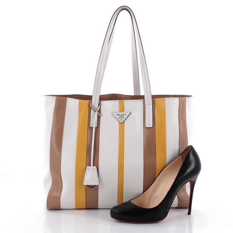 This authentic Prada Baiadera Tote Calfskin Medium is a chic, vividly hued tote perfect for the modern fashionista. Crafted from white, brown and yellow calfskin leather, this stylish bag features dual flat leather handles, inverted triangle Prada