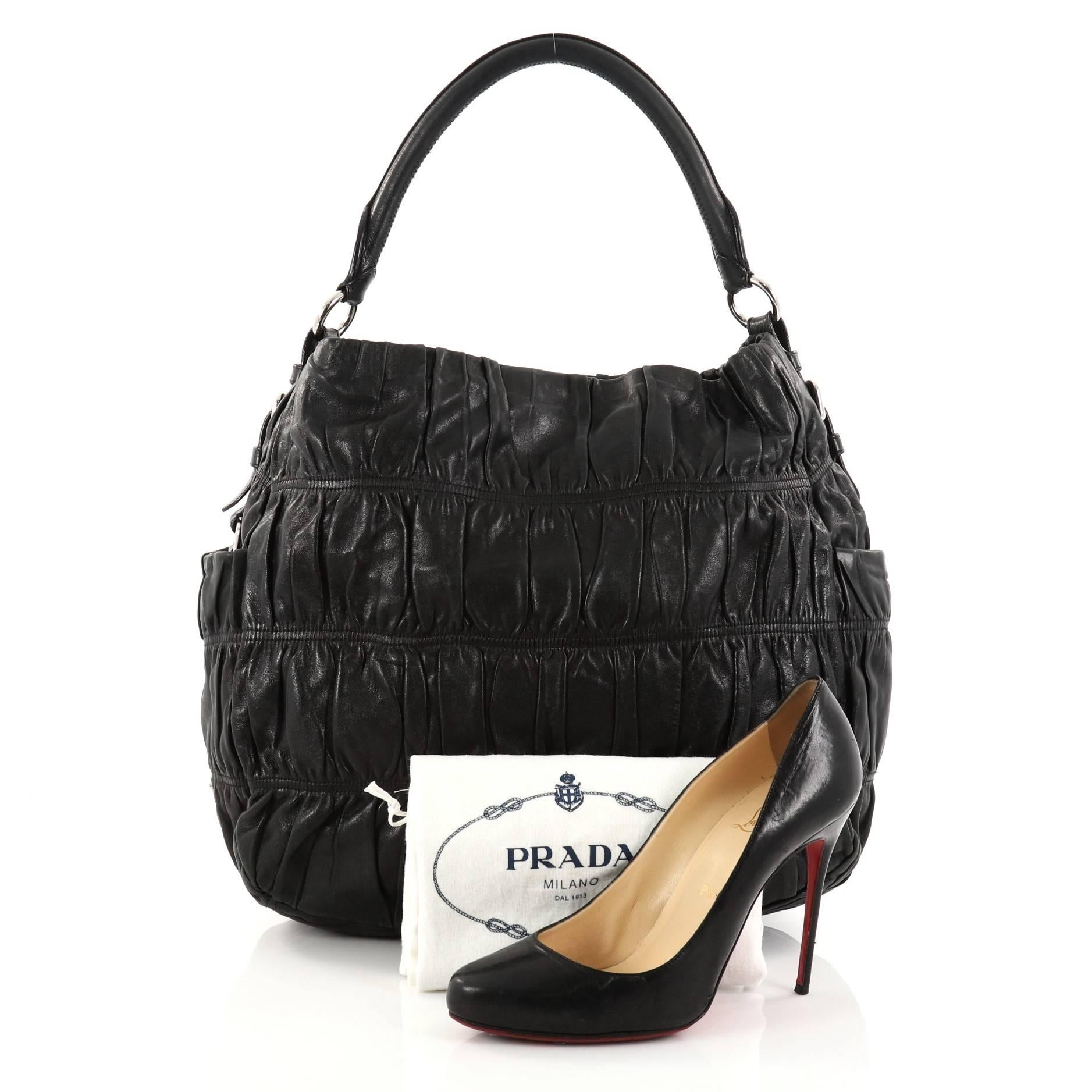 This authentic Prada Gaufre Side Pocket Hobo Nappa Leather Large is a stylish and easy-to-carry bag. Crafted from black ruched nappa leather, this hobo features a rolled leather handle, two exterior side flat pockets, protective base studs, Prada