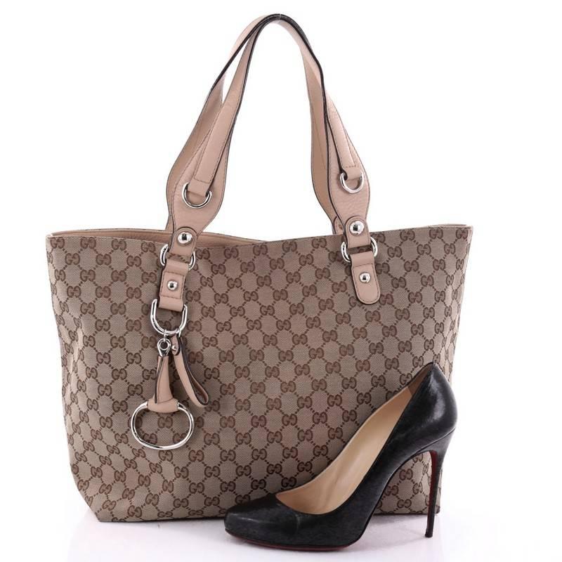 This authentic Gucci Icon Bit Tote GG Canvas Medium is classic and sophisticated in design perfect for everyday casual look. Crafted in brown gg canvas, this tote features icon bit charms, dual leather handles, protective base studs and silver-tone