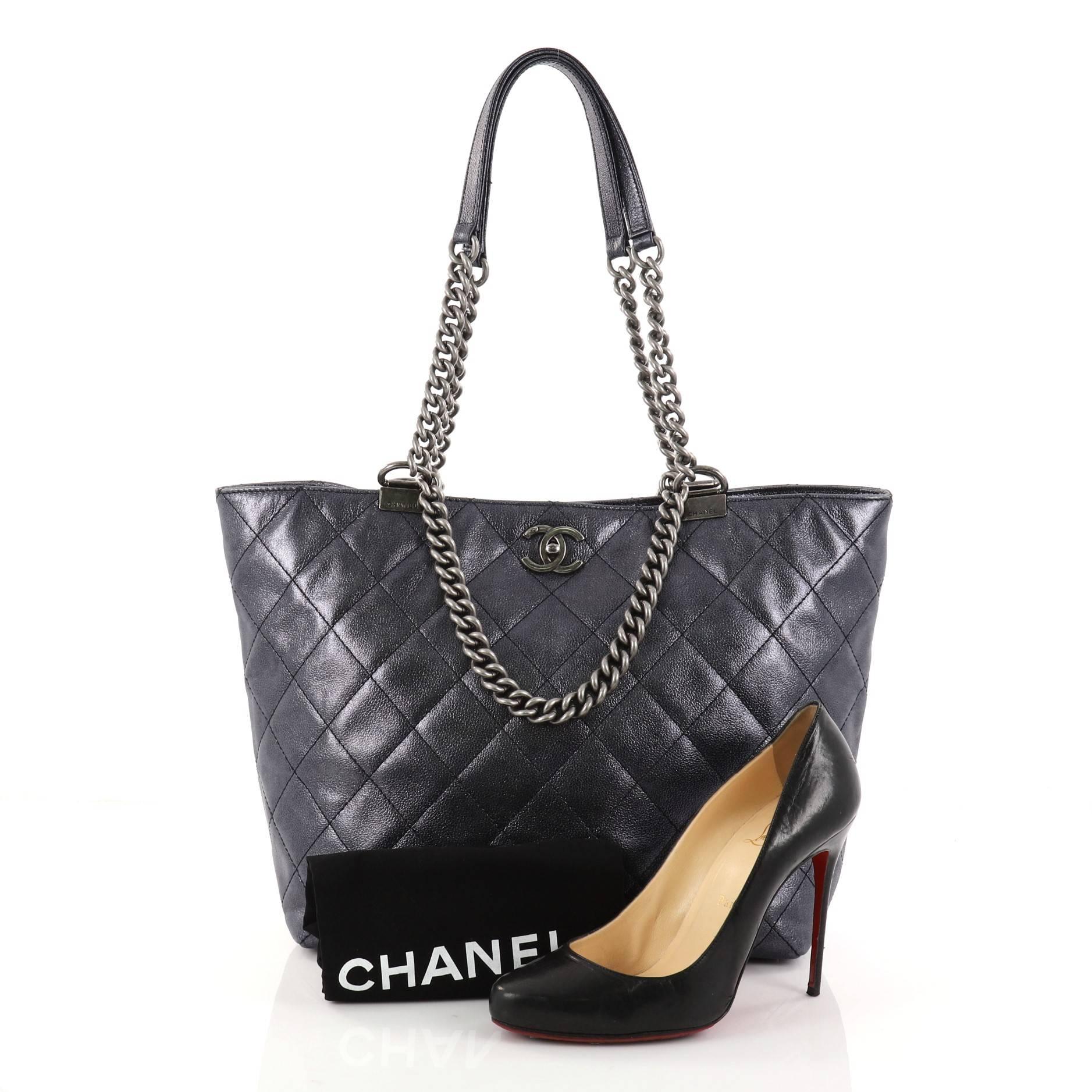 This authentic Chanel Shopping In Chains Tote Quilted Calfskin Large is the perfect luxe companion for the modern woman. Crafted in blue quilted metallic calfskin, this simple yet elegant tote features shoulder straps with aged silver chunky chain