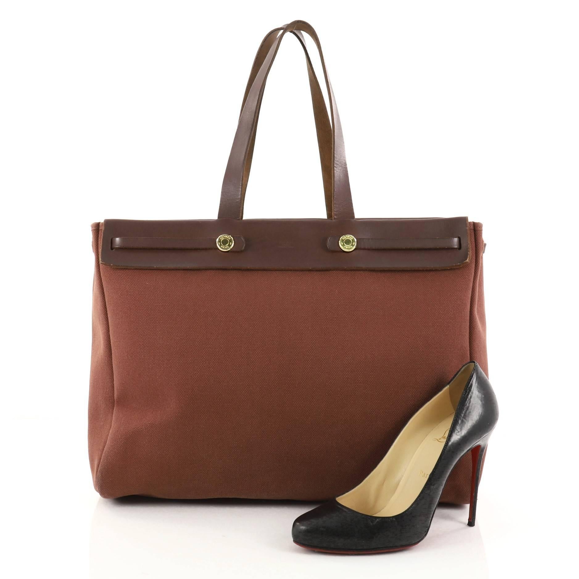 This authentic Hermes Herbag Cabas Toile and Leather MM is a fabulously functional, lightweight tote made for everyday excursions. Constructed from burgundy toile and vache hunter leather, this versatile tote features a flat leather top handle, gold