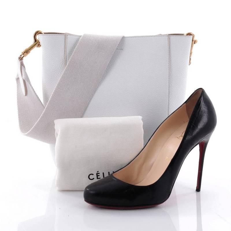 This authentic Celine Sangle Seau Handbag Calfskin Small balances a simple yet luxurious style perfect for an on-the-go woman. Crafted from white calfskin leather, this minimalist bucket bag features a canvas shoulder strap and gold-tone hardware