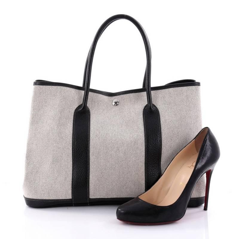 This authentic Hermes Garden Party Tote Leather 36 is an elegant and simple tote made for all seasons. Crafted from black veau negonda leather and natural toile, this chic everyday tote features dual-rolled leather top handles, stand-out contrast