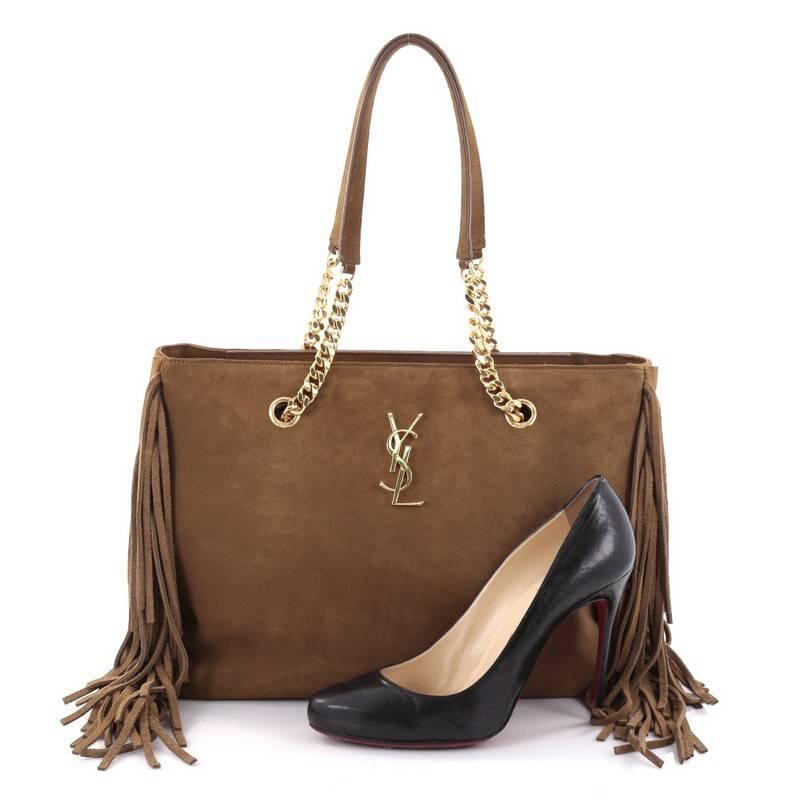 This authentic Saint Laurent Classic Monogram Tote Fringe Suede Large is a classic piece with a twist perfect for your casual wear. Crafted in tan suede, this tote features cascading fringe on both sides, dual slim suede handles with curb-chain