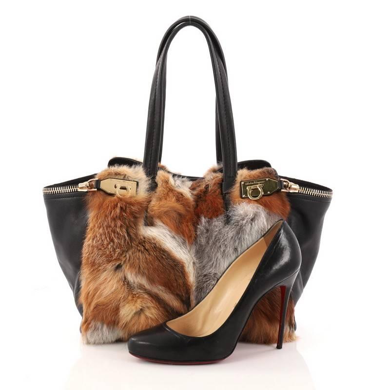 This authentic Salvatore Ferragamo Verve Tote Fox Fur and Leather Medium is a casual yet chic tote perfect for everyday excursions. Crafted from black leather and multicolored fox fur, this elegant bag features dual flat handles, two side zipped