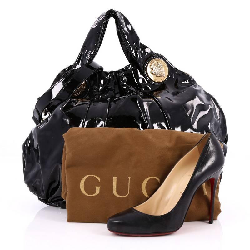 This authentic Gucci Hysteria Convertible Top Handle Bag Patent Large is a lovely accessory for any Gucci lover showcasing an easy-casual yet elegant design. Crafted from black patent leather, this luxurious hobo showcases dual shoulder straps with