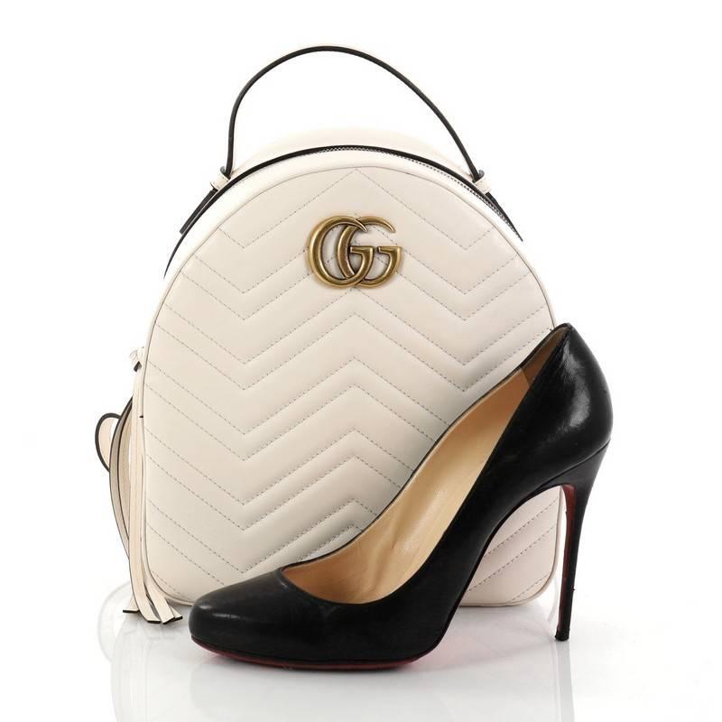 This authentic Gucci GG Marmont Backpack Matelasse Leather Small is a luxurious stylish backpack ideal for on-the-go fashionistas. Crafted from off-white matelasse chevron quilted leather, this bag features a top handle, adjustable backpack straps,