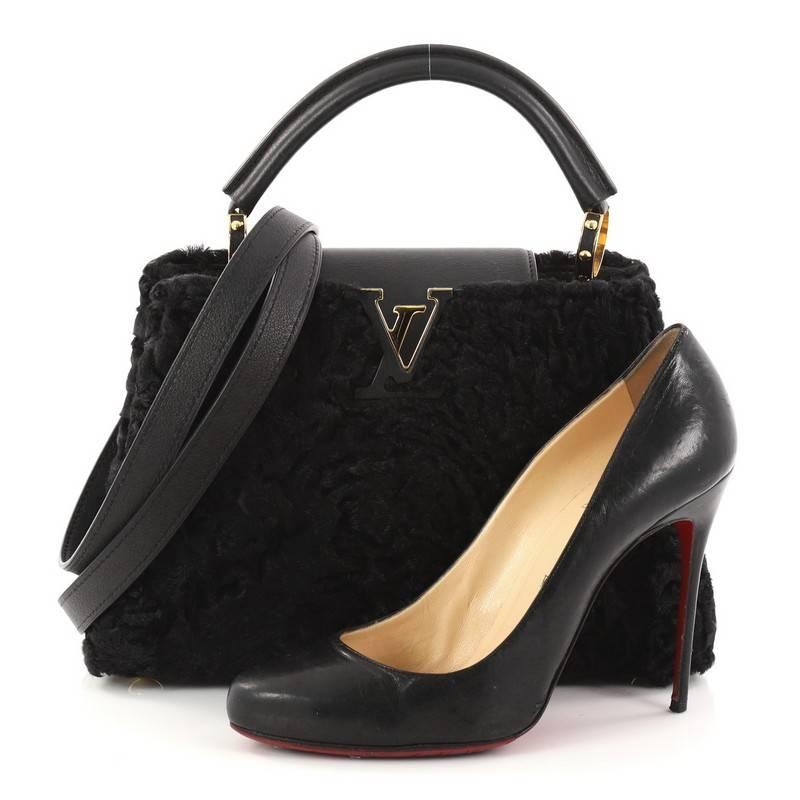 This authentic Louis Vuitton Capucines Handbag Astrakhan Fur BB displays an exalted level of craftsmanship perfect for the stylish fashionista. Crafted from black astrakhan fur, this ultra-chic petite bag features a single rolled leather handle