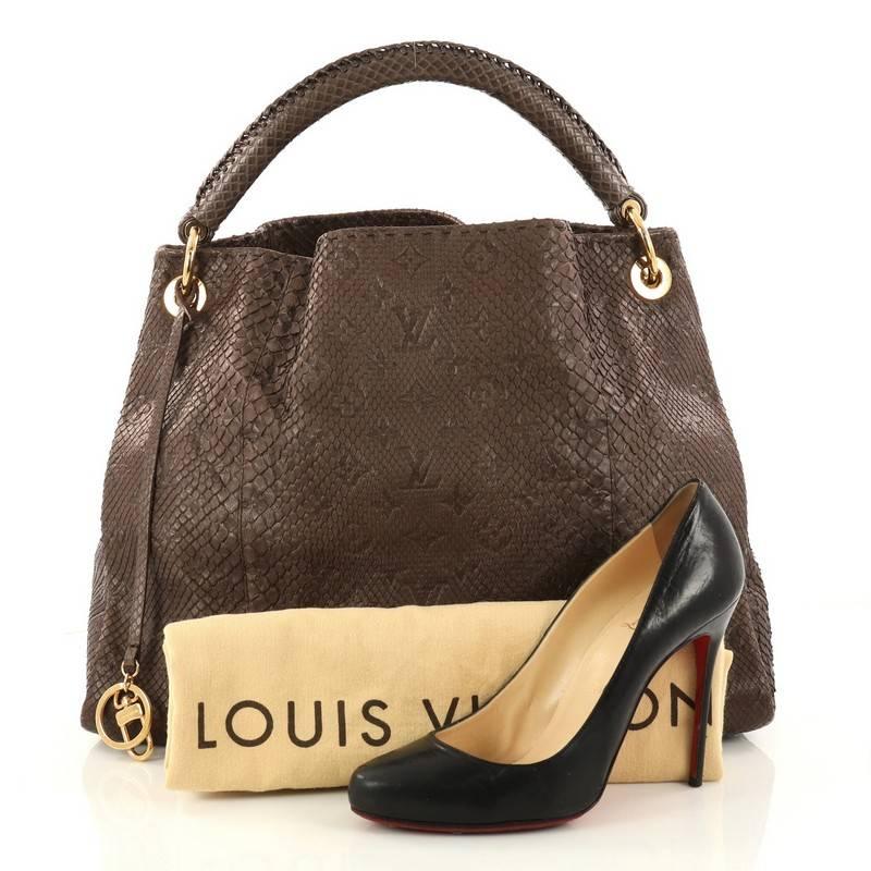 This authentic Louis Vuitton Artsy Handbag Monogram Embossed Python MM is as elegant as it is sturdy. Crafted from genuine dark taupe monogram embossed python skin, this luxurious and refined hobo features a single looped top handle with polished
