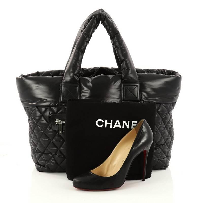 This authentic Chanel Coco Cocoon Zipped Tote Quilted Nylon Large is a highly sought after piece from Lagerfeld's fun and chic Coco Cocoon line. Crafted from black quilted nylon, this sporty-chic tote features dual padded top handles, exterior zip