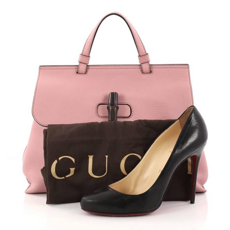 This authentic Gucci Bamboo Daily Top Handle Bag Leather Medium is perfect for everyday use. Crafted from pink leather, this gorgeous bag features flat top handle, side magnet detailing, flap turn-lock closure with dark lacquered bamboo detail, and