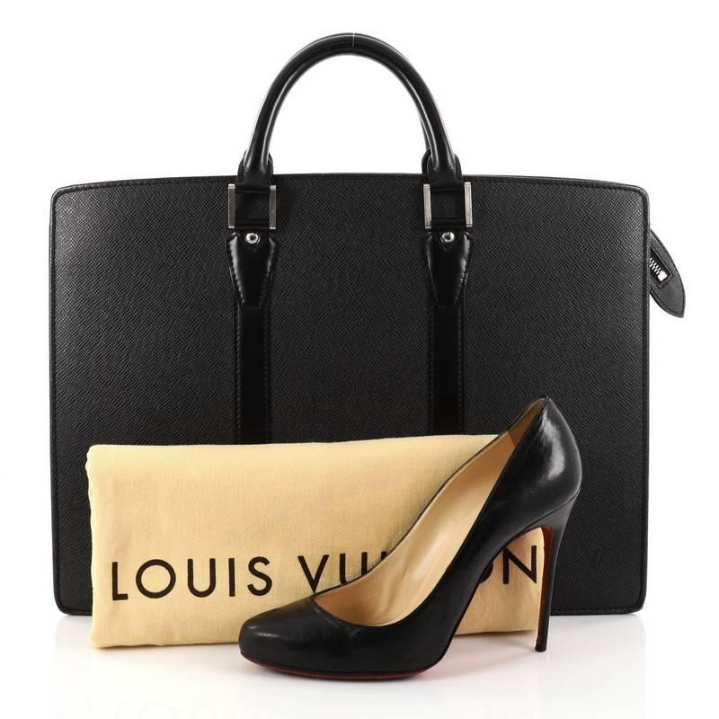 This authentic Louis Vuitton Lozan Handbag Taiga Leather showcases a traditional briefcase silhouette with a luxurious urban spin. Crafted from black taiga leather, this structured satchel features dual-rolled top handles, matching smooth leather