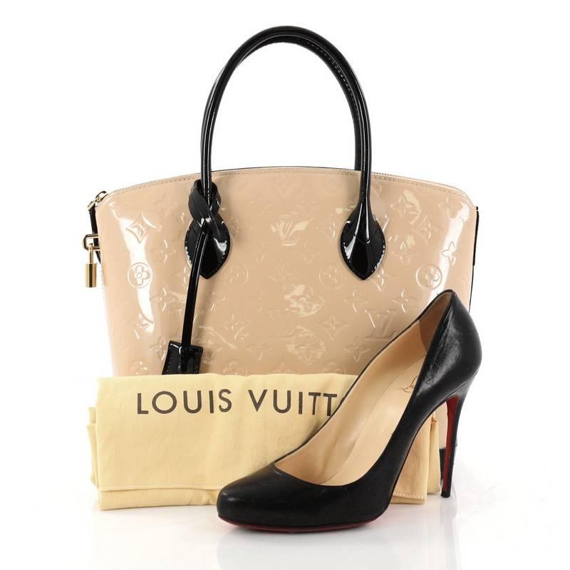 This authentic Louis Vuitton Lockit Handbag Monogram Vernis PM mixes the brand's penchant for timeless design with modern flair. Crafted from nude embossed monogram vernis leather with contrasting smooth black patent leather trims, this chic bag
