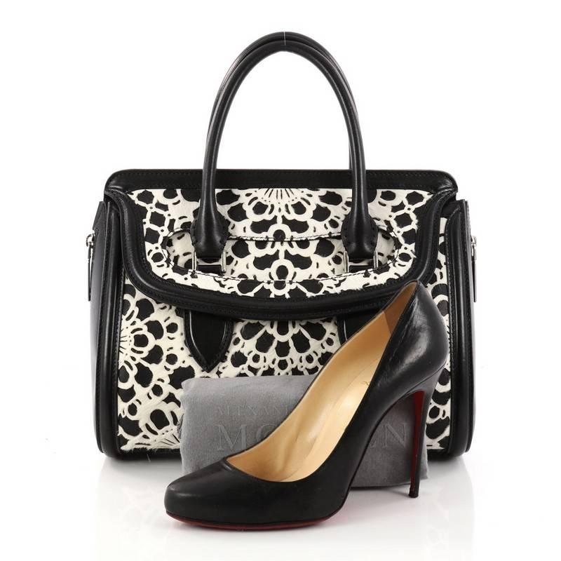 This authentic Alexander McQueen Heroine Tote Laser Cut Calf Hair and Leather East West combines functional style with luxurious design. Crafted in black leather and laser cut white calf hair, this structured bag features dual-rolled leather