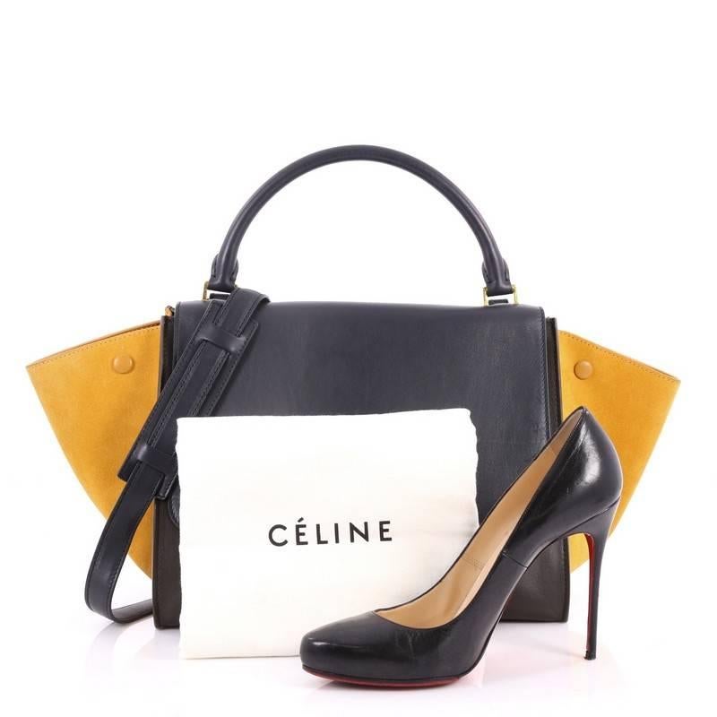This authentic Celine Tricolor Trapeze Handbag Leather Medium is a modern minimalist design with a playful twist in an array of subdued colors. Crafted from yellow suede, navy and black leather, this popular bag features gold-tone hardware accents,