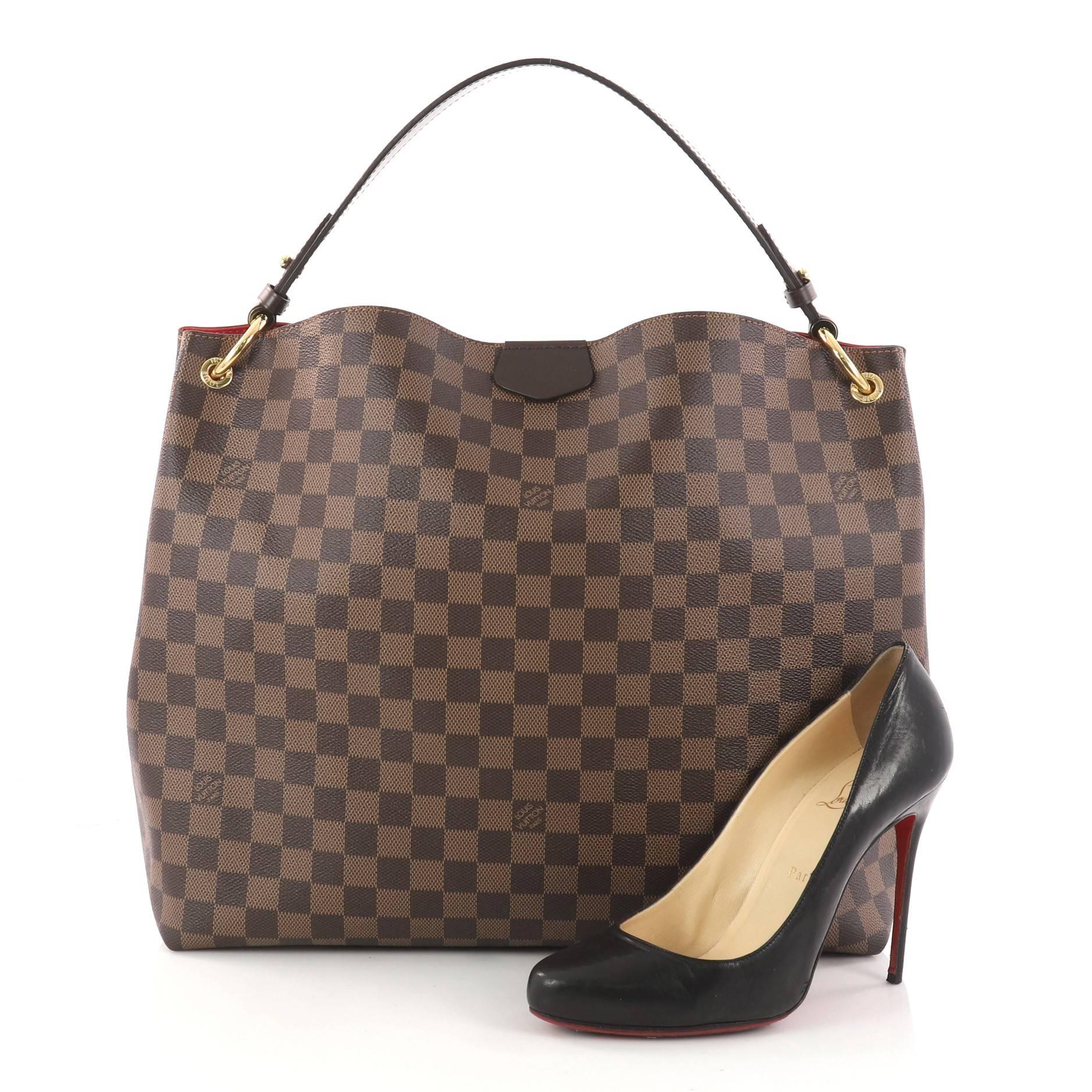 This authentic Louis Vuitton Graceful Handbag Damier MM from 2018 is a stylish bag that's sure to be an instant favorite. Crafted in damier ebene coated canvas, this gorgeous bag features a flat leather shoulder strap, dark brown leather trims, and