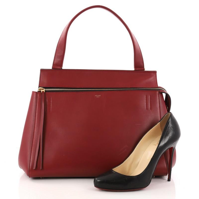 This authentic Celine Edge Bag Leather Small showcases brand's simplicity and understated modern design perfect for modern woman. Crafted in red leather, this structured bag displays a single looped black strap, exterior snap back pocket and